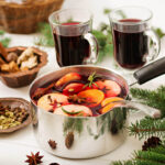 Homemade Christmas potpourri made with dried orange slices, cinnamon sticks, star anise, cloves, cranberries, and fresh evergreen sprigs, beautifully arranged in a rustic bowl.