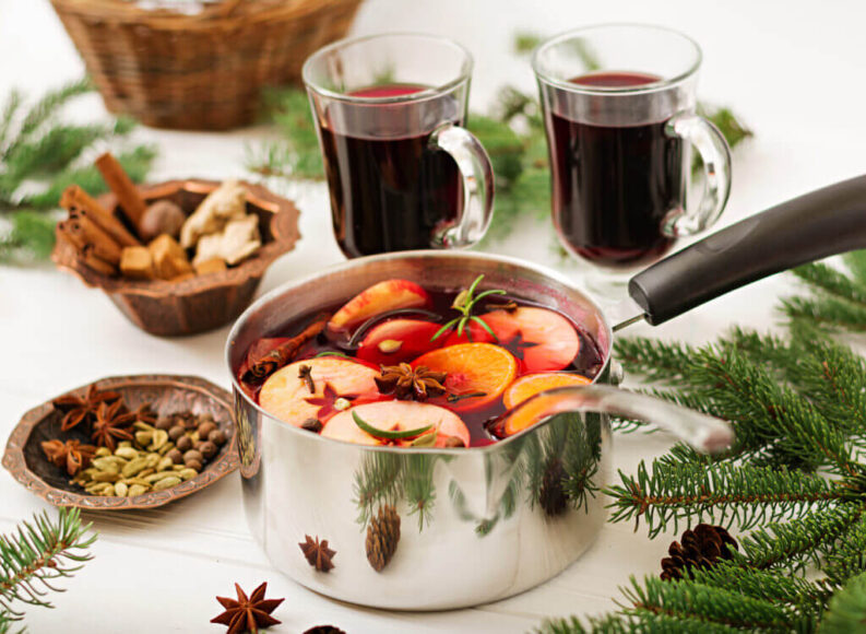 Homemade Christmas potpourri made with dried orange slices, cinnamon sticks, star anise, cloves, cranberries, and fresh evergreen sprigs, beautifully arranged in a rustic bowl.